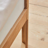 FLEXA BABY bed, oak finish, 140x70 cm with mattress on light wooden floor; rounded edges for child safety.